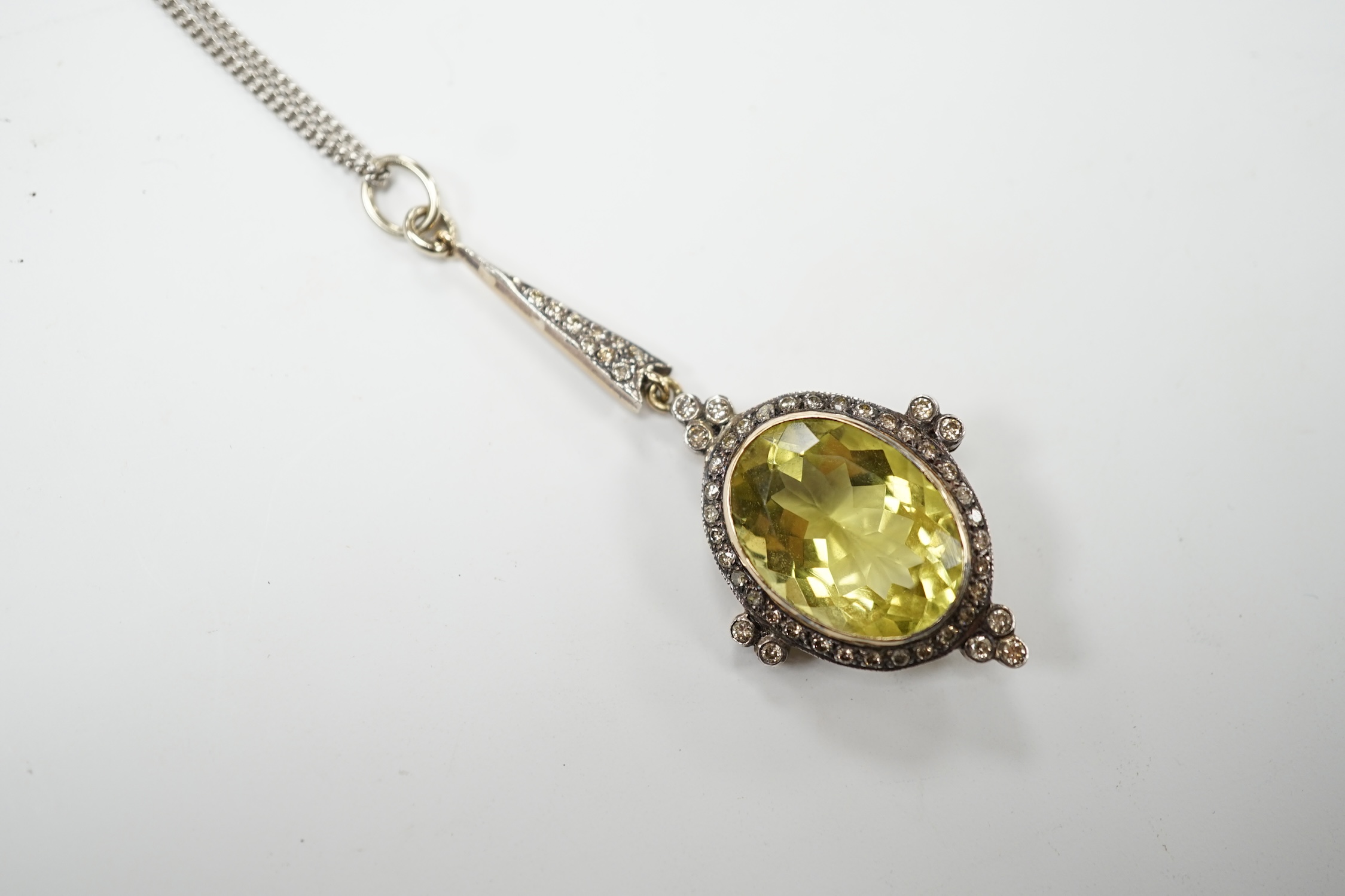A late Victorian yellow metal and single stone oval cut citrine set drop pendant, with diamond set border and bale, 53mm, on a later 375 white metal chain, 50cm, gross weight 11.2 grams. Good condition.